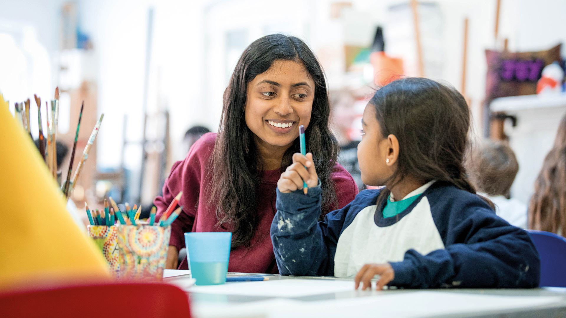 Child and smiling carer enjoying an art activity.