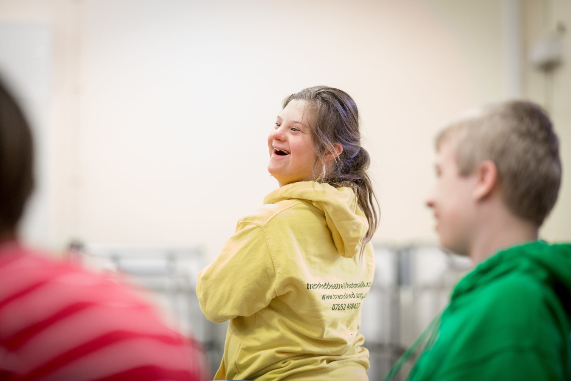 Young girl in yellow hoody laughing in a group class