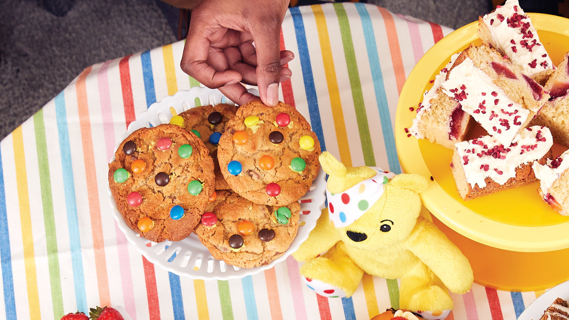 Person picking up a colourful chocolate chip cookie.