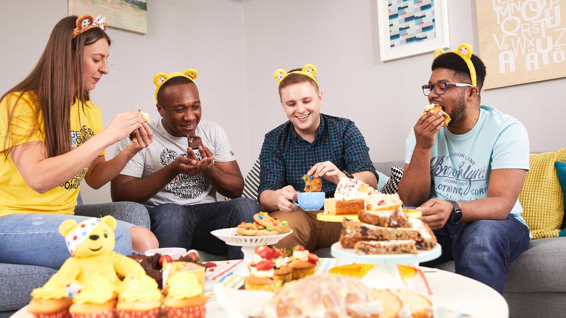 A group of adults sat eating cake wearing BBC Children in Need merchandise