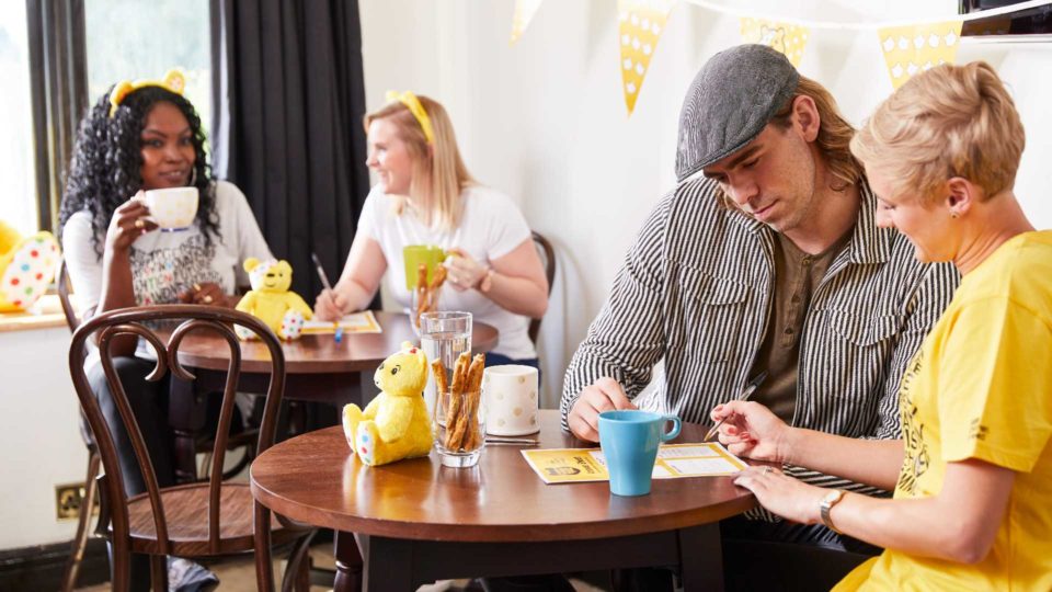 Adults taking part in Pudsey's Big BBC Quiz in a café