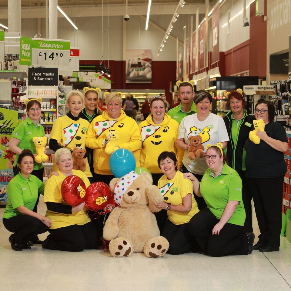 A group of ASDA fundraising colleagues in Children in Need clothing with a Pudsey bear