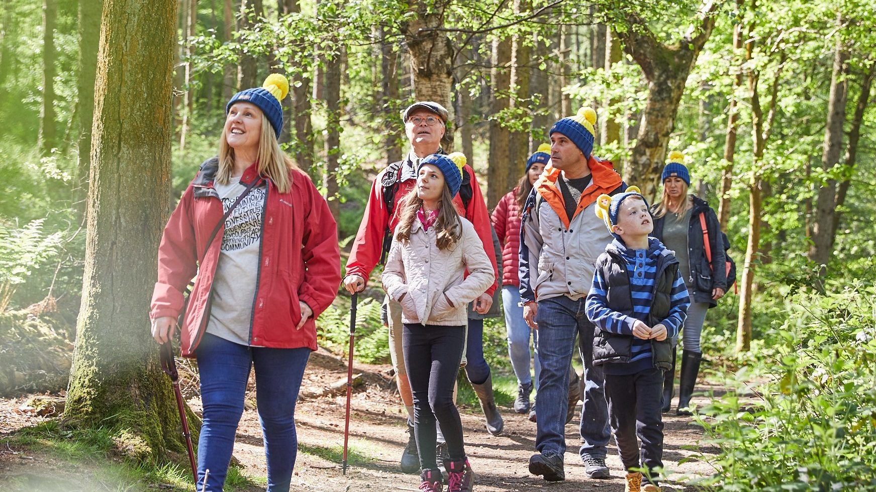 Family in Countryfile ramble hats walking through trees together