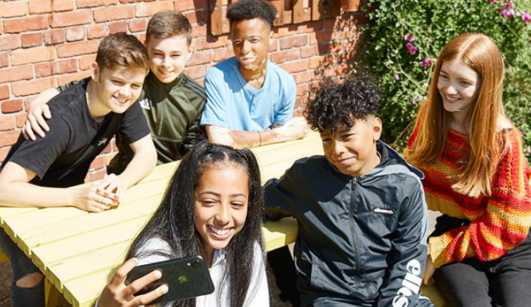 Group of teenagers taking a selfie around a table