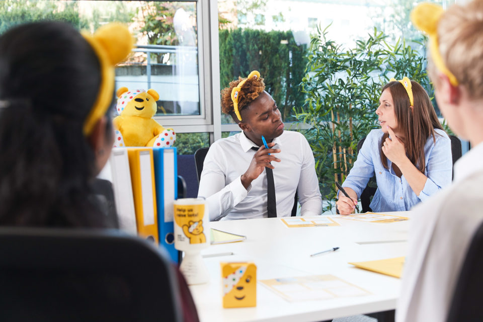 Image of people sitting round a table participating in an office quiz
