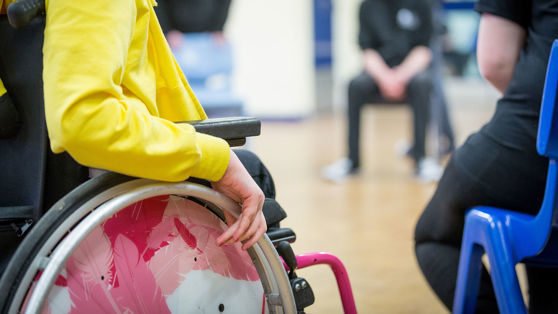 Close up of a girl's hand on her wheelchair in a group of volunteers