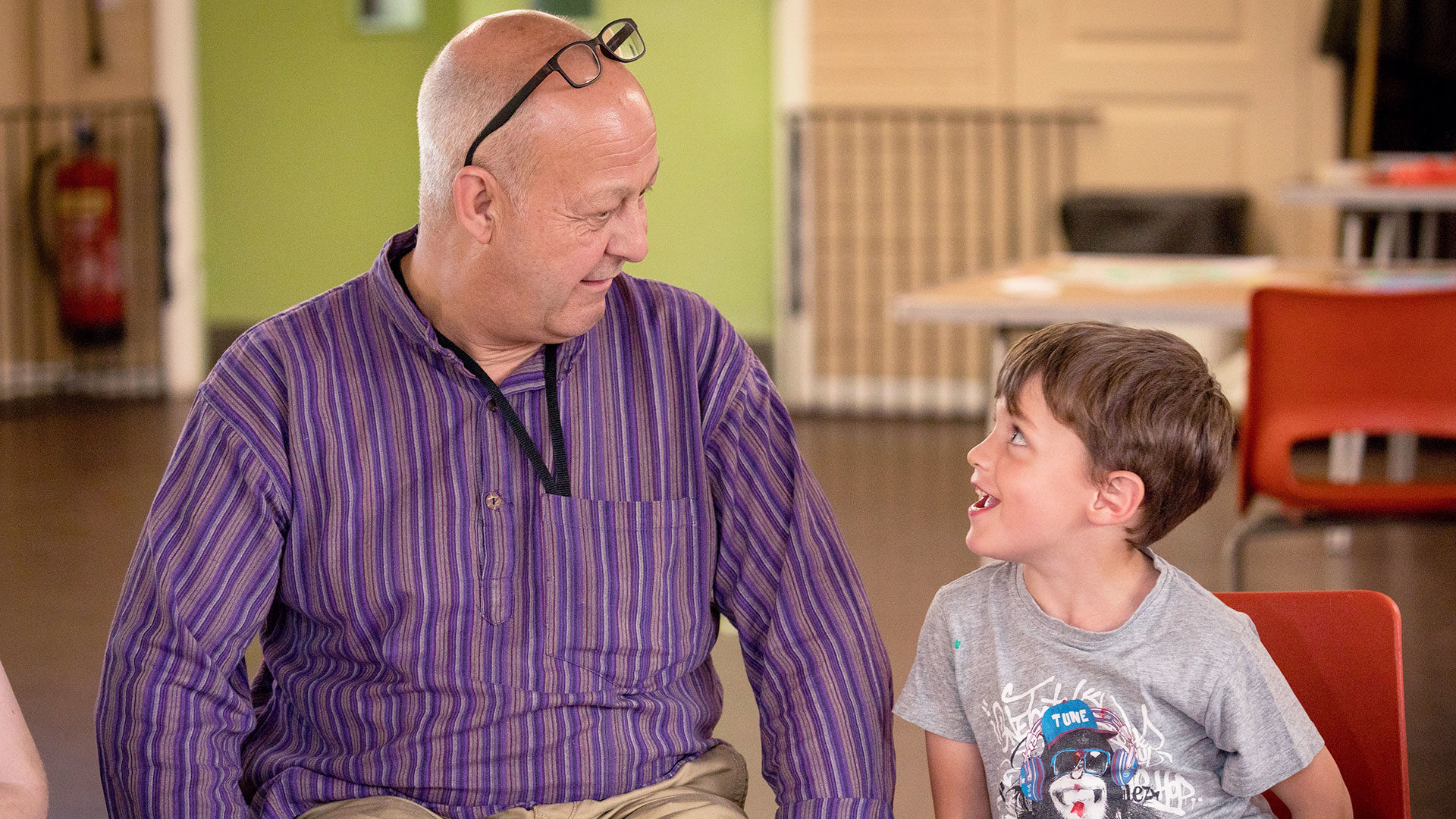 Young boy laughing at an older male volunteer in a group session