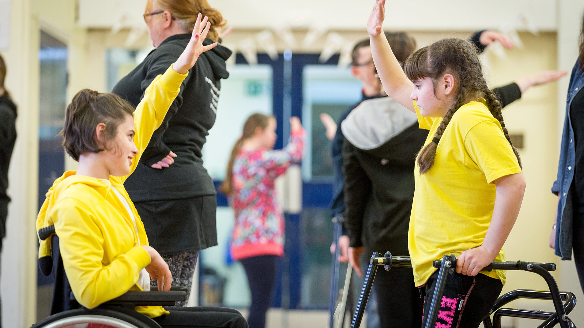 Two children play sport- one is in a wheelchair and one is using a walking frame