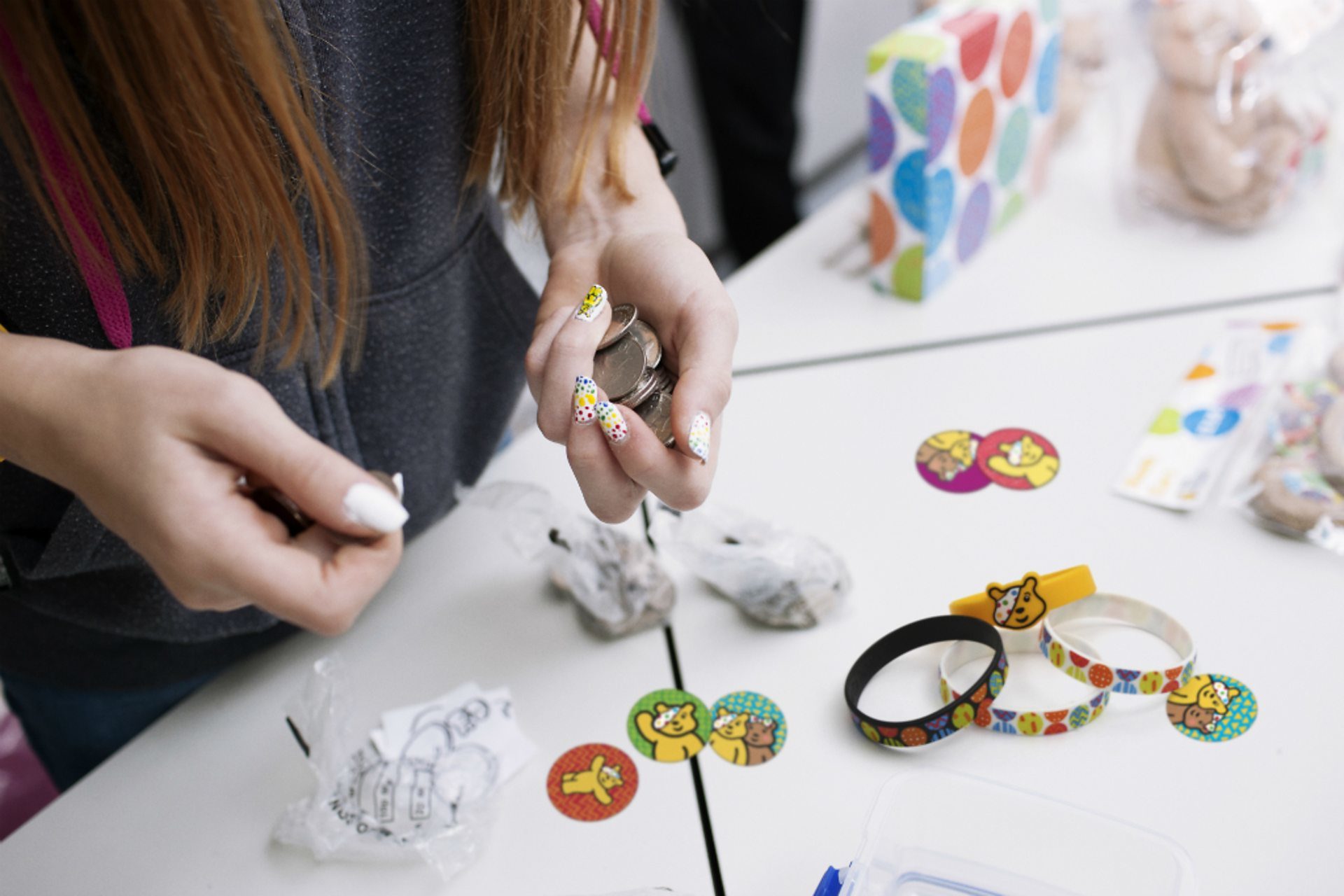 A female teenager collecting money for selling BBC Children in Need merchandise.