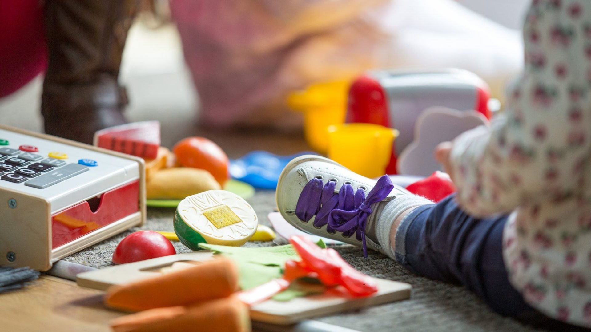 A child sat amongst colourful toys on the floor