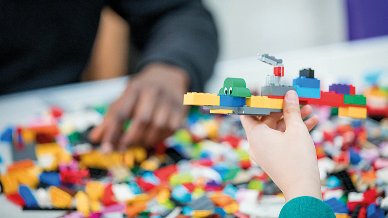 Two children playing with small building blocks and building a flying machine