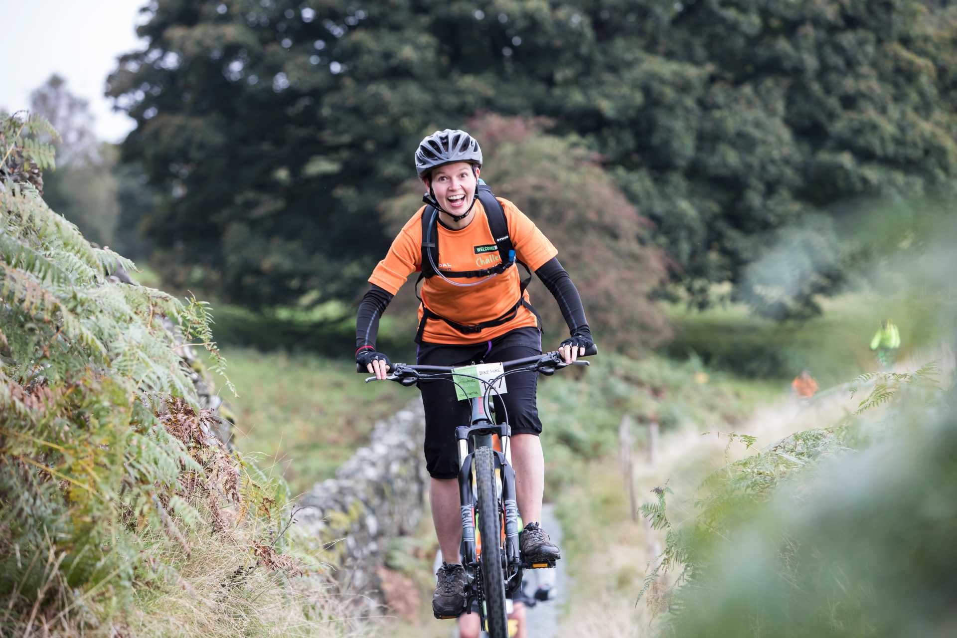 A lady cycling in the countryside wearing sports clothing and a helmet