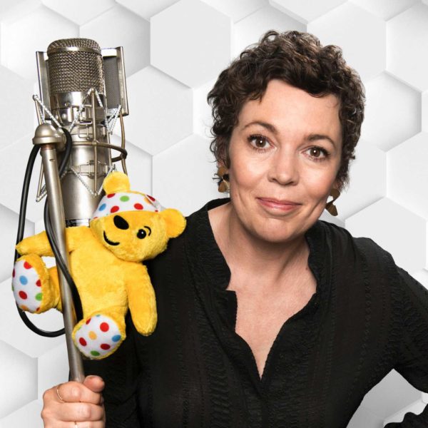 Olivia Coleman in front of a microphone holding a Pudsey toy