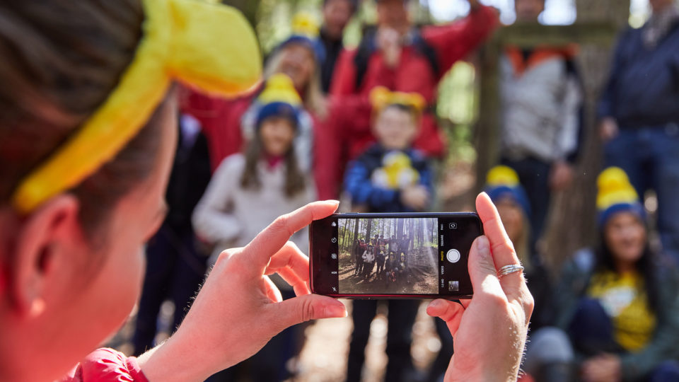 A group of people having their photo taken on a phone whilst out on a Ramble walk, the focus being on the phone picture