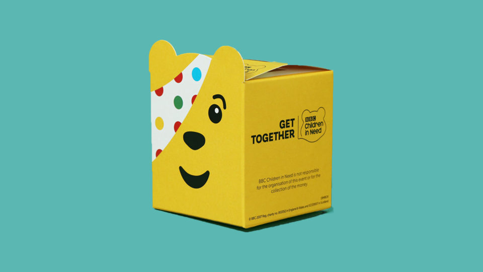 A mini Pudsey moneybox on a teal background, made up using the cut out on our site