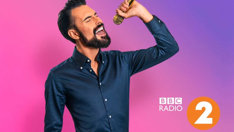 Rylan holding a micrphone with the Radio 2 logo