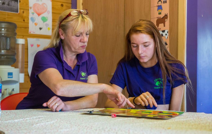 A woman and a girl play a board game about horses