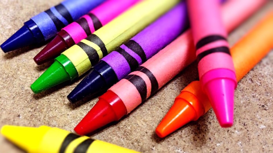 A number of coloured crayons spread across paper