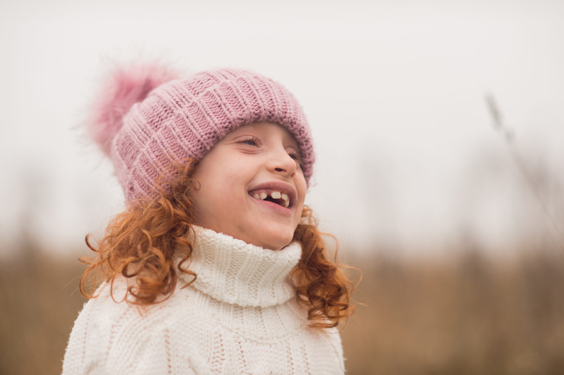 A photo of Olivia in a field wearing a pink bobble hat