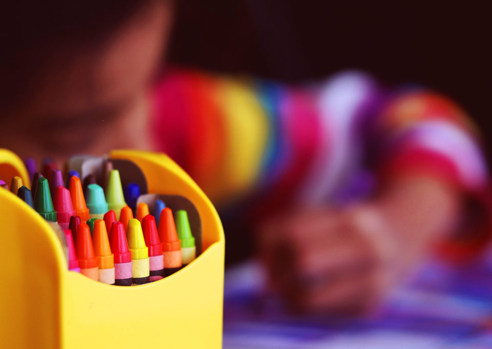 A young child drawing with crayons
