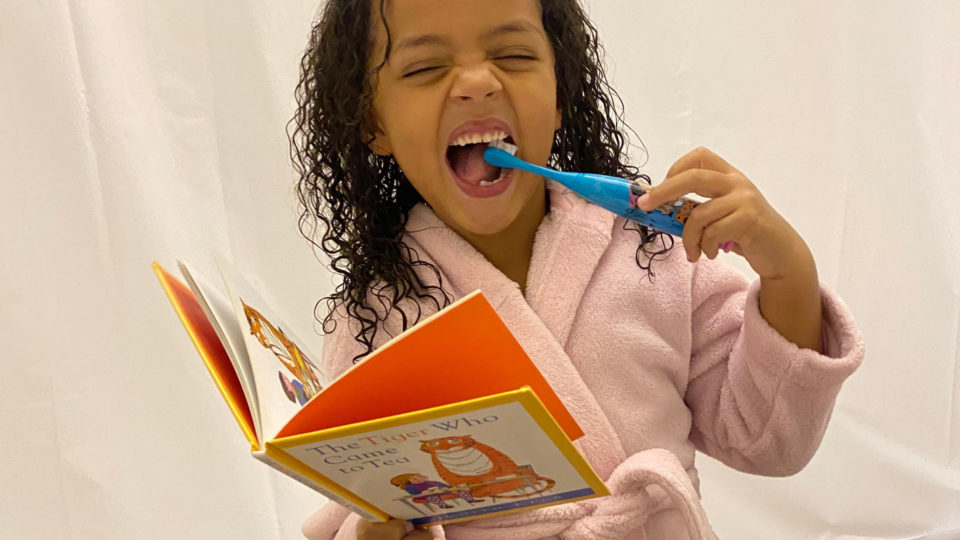 Nee reading a book and brushing her teeth