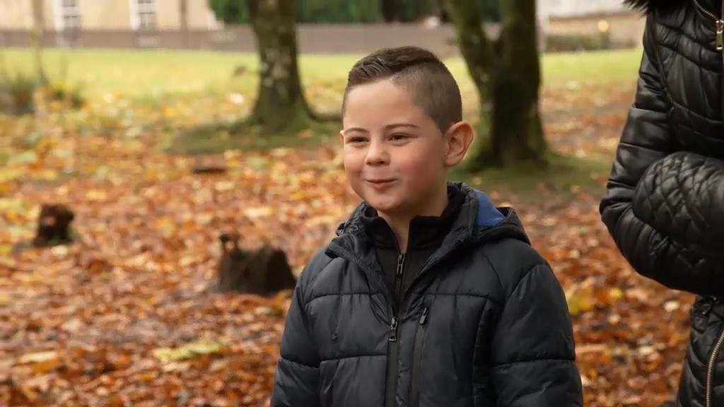 Nathan with trees behindhim and autumnal leaves on the floor