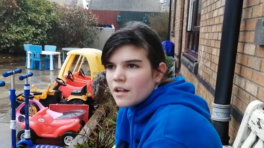 An image of a child in a playground with push along car toys in the background