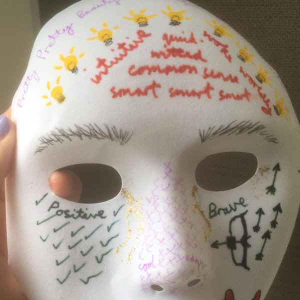 a white paper mask with words relating to a person's identity drawn on it fel tip pens