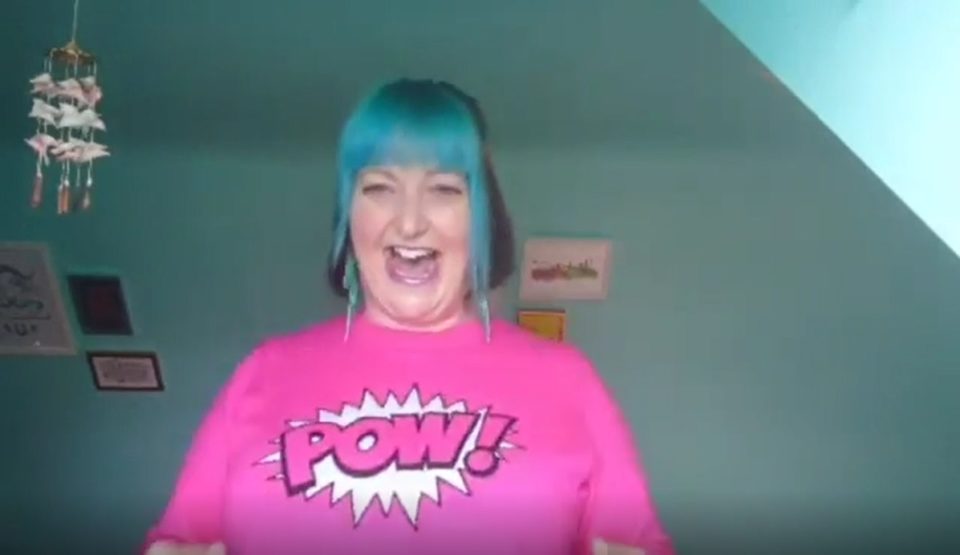 a lady with blue hair and a bright pink jumper laughing