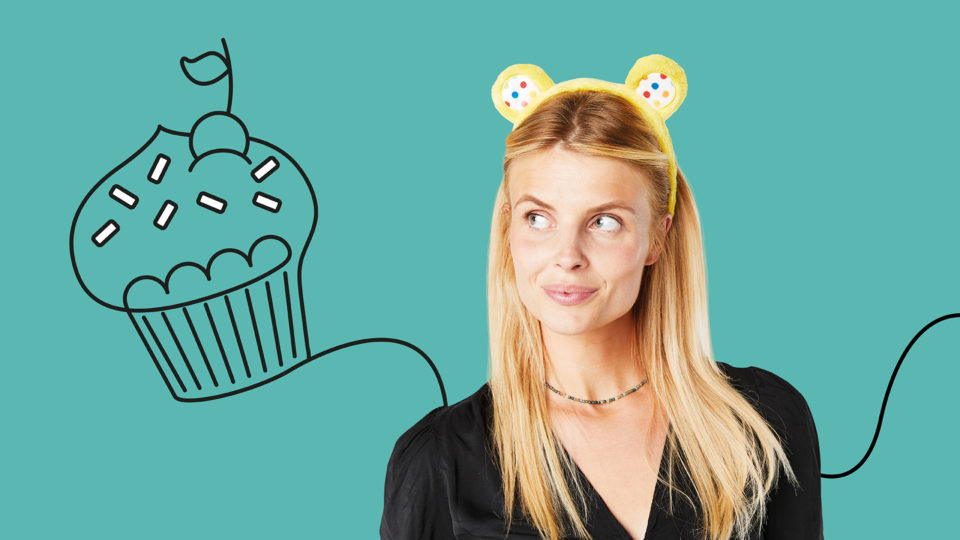 a lady wearing Pudsey ears with a freehand drawing of a cupcake in the background
