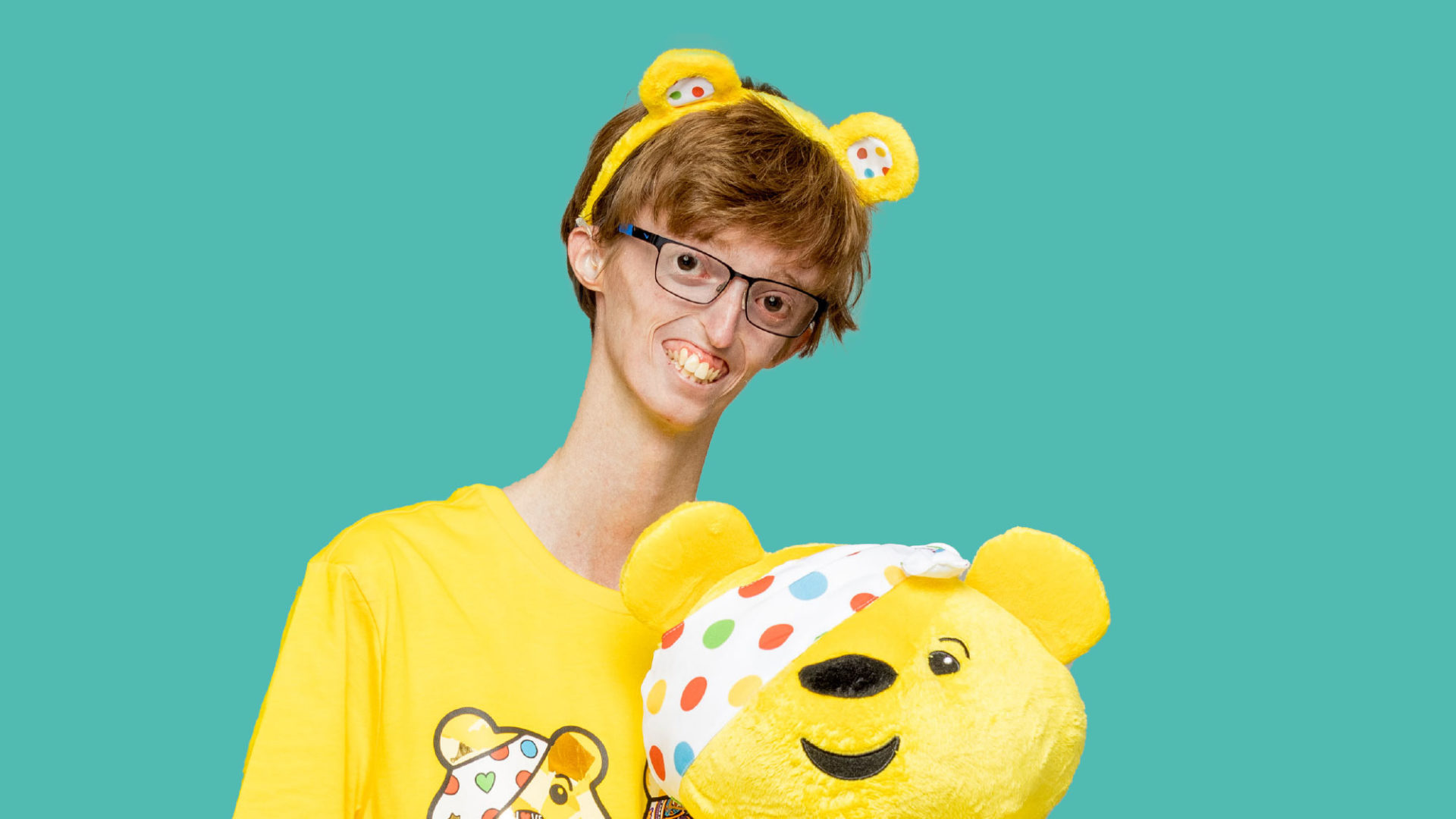 Dylan hlding a pudsey bear toy adn wearing ears