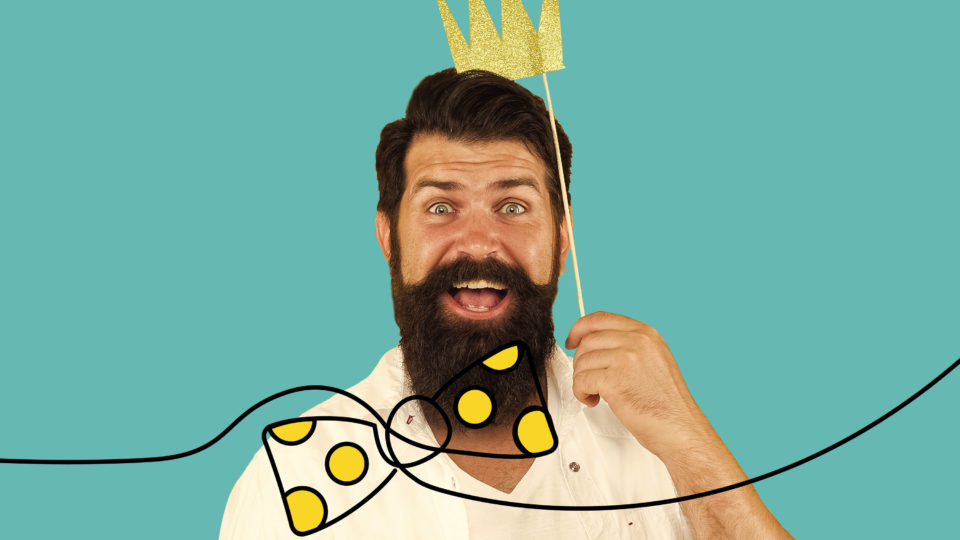 A man in a beard holding a paper crown with an illustrated bowtie