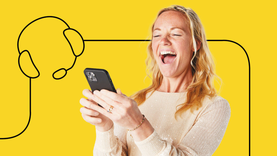 a lady laughing whilst she holds a mobile phone