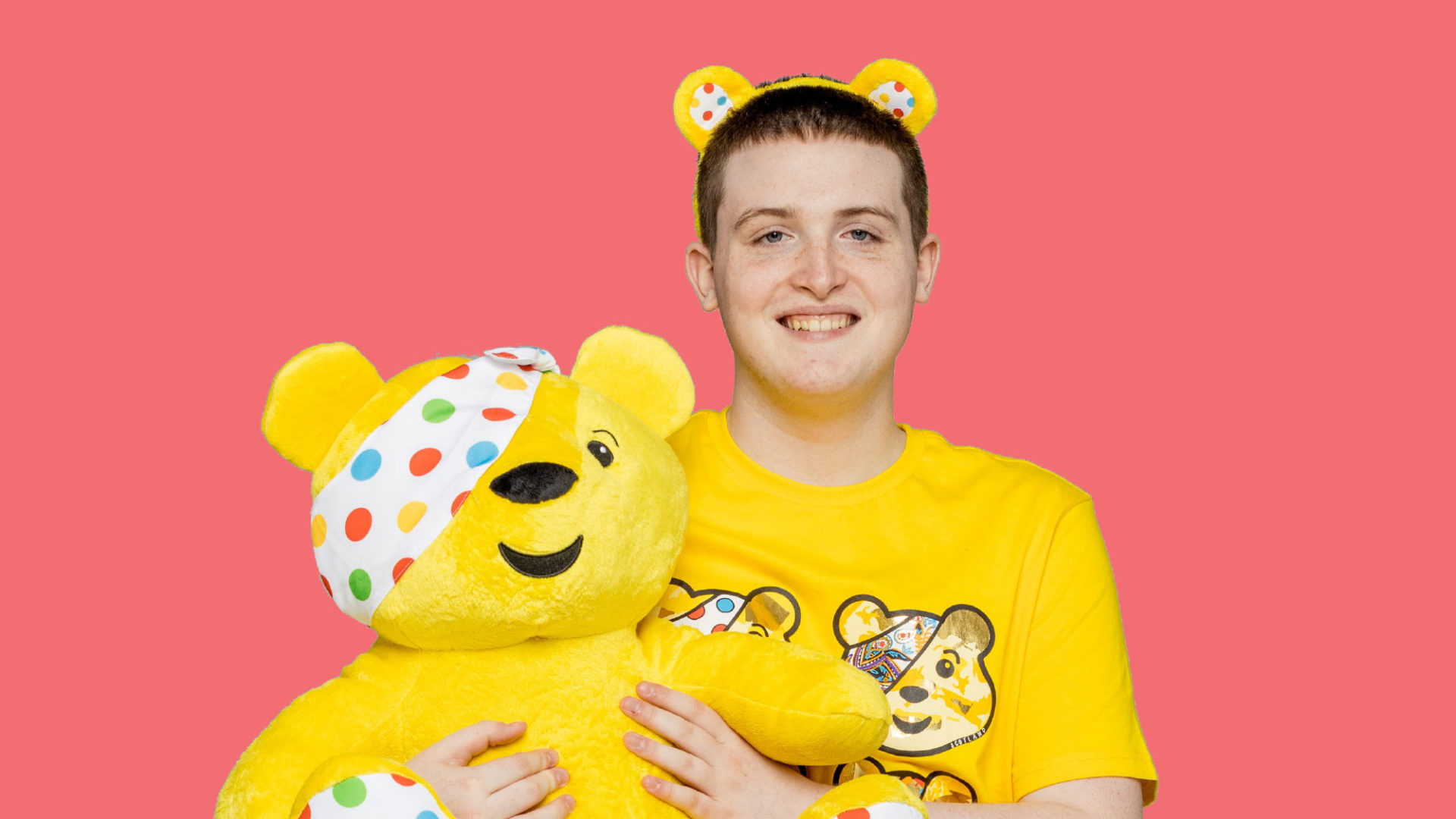 Nathan holding a pudsey bear toy and wearing pudsey ears