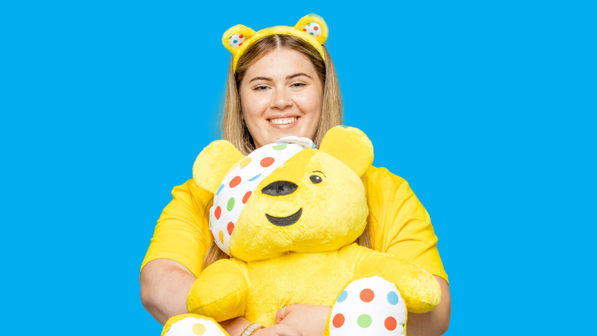 Roisin holding a pudsey bear toy and wearing ears