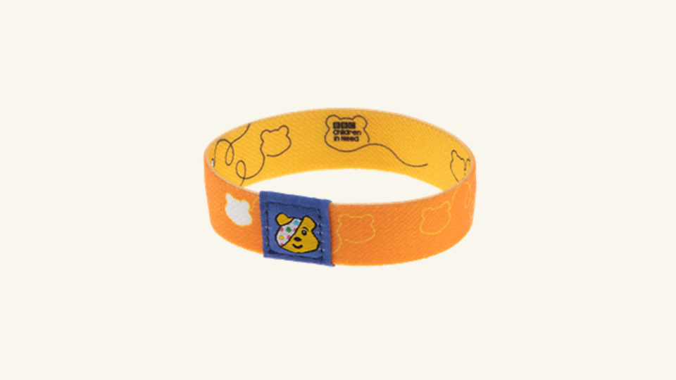 A yellow wristband with Pudsey head shapes