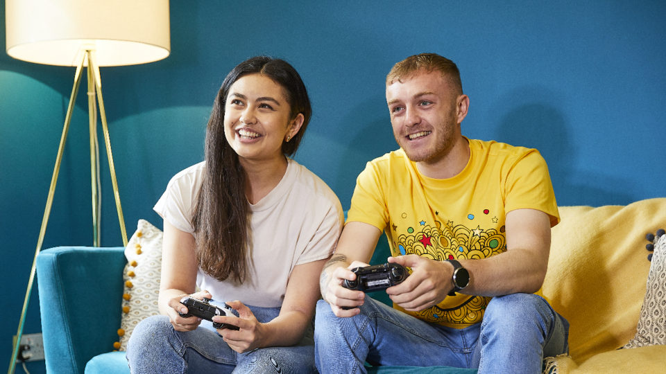 two young adults on a sofa holding a video game controller