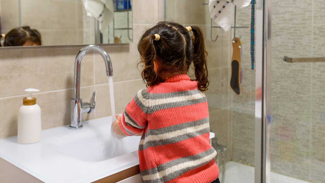 A child washiing their hands at a basin in a domestic bathroom