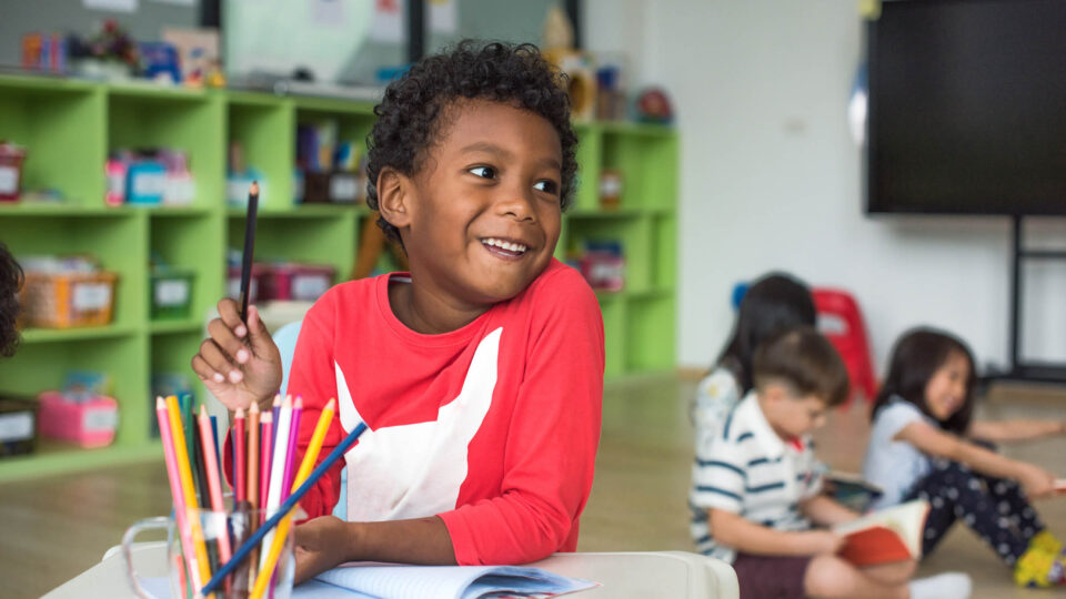 Children drawing at tables in a classroom setting