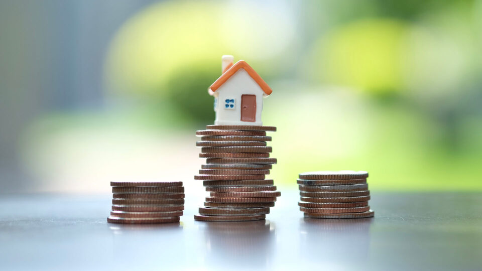 A small plastic house on top of a stack of pennies