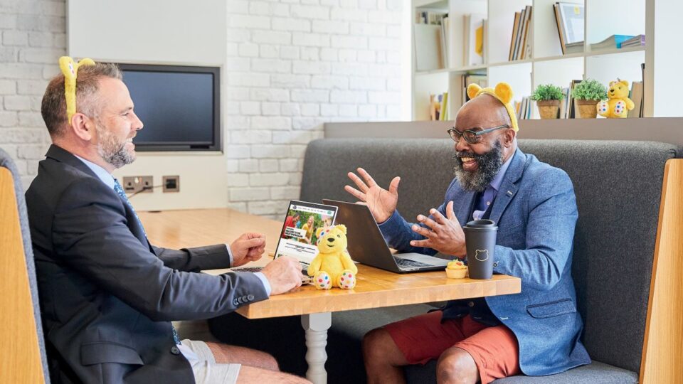 Two people in a business setting have come to work in their 'zoom outfit' wearing a jacket and tie along with casual shorts