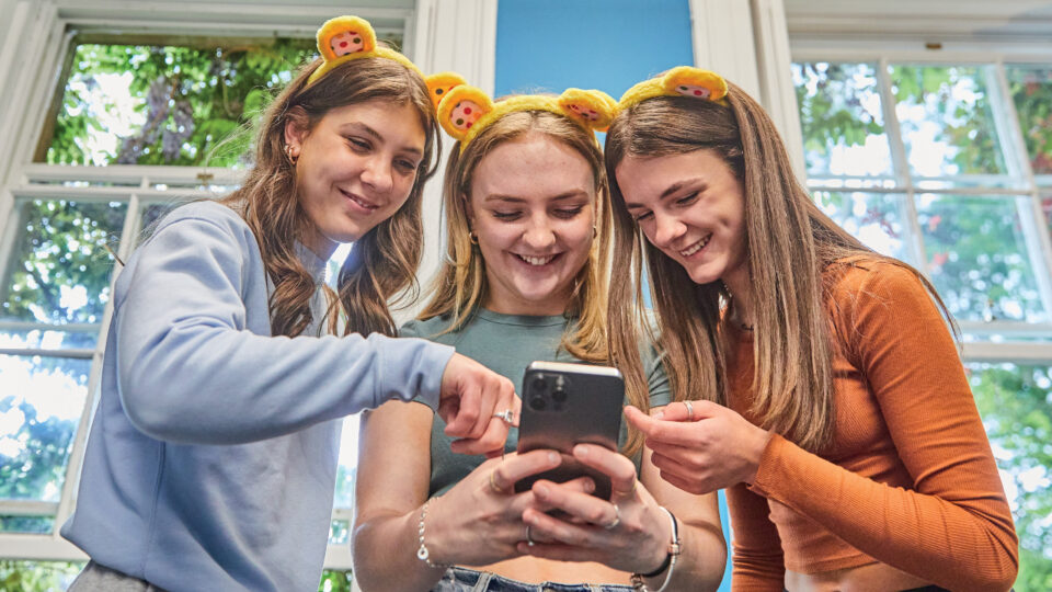 young people look at phone together whilst wearing Pudsey ears
