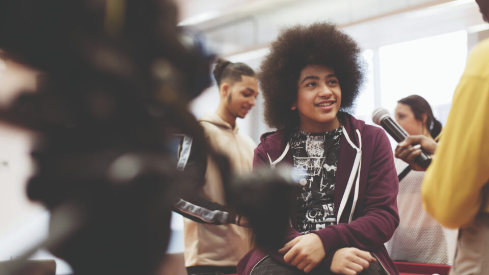 Young person surrounded by camera and microphone equipment