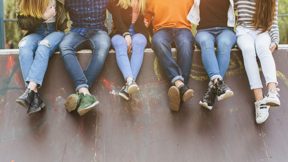 Young people sitting in a row in a skate park