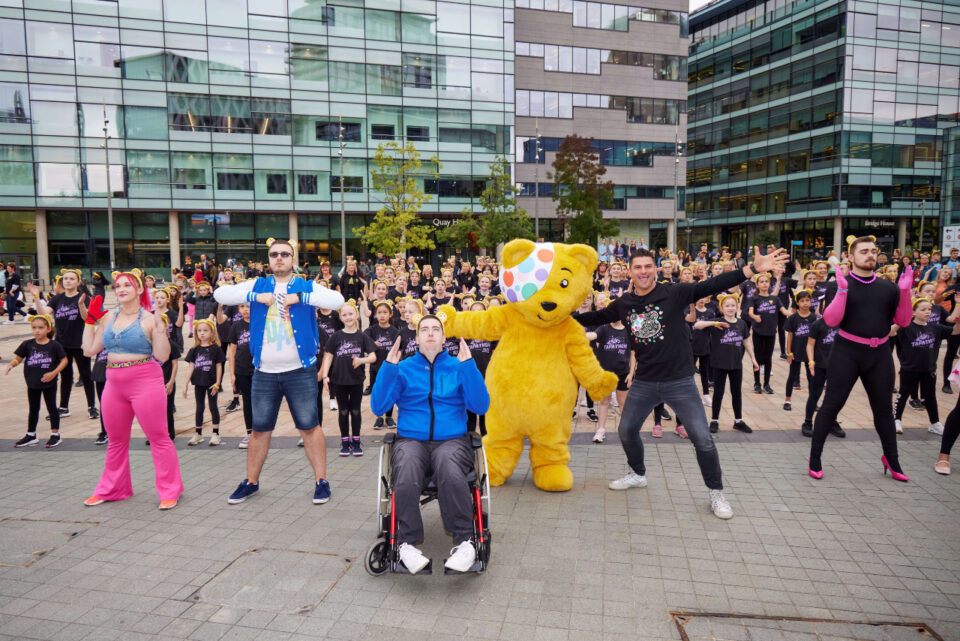 Aljaz Dylan and Pudsey are leading a group of dancers in a live dancing event outside BBC Salford offices