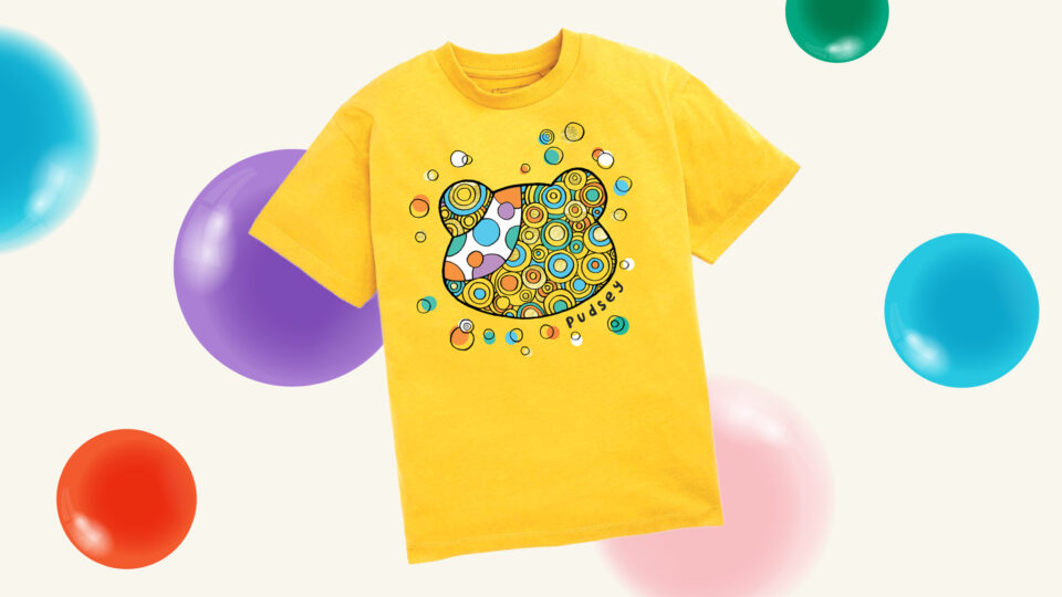 A yellow tshirt with a colourful Pudsey head design