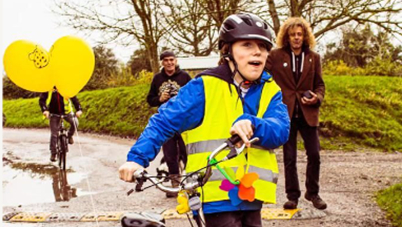 Thomas wearing a cycling helmet holding the handlebars of a Rickshaw