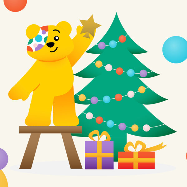 Pudsey placing a start on top of a christmas tree