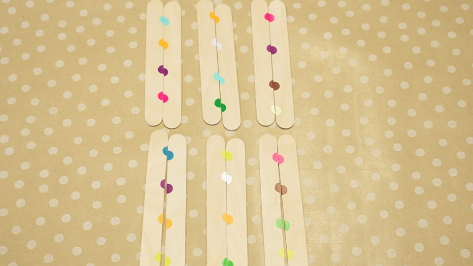 lolly sticks with coloured dots on a table