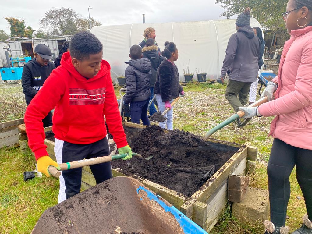 young people with spades, gaterhing compost from a large wooden container